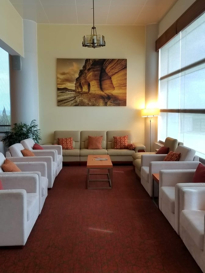 The seating area in the Executive Lounge at V. C. Bird International Airport features comfortable armchairs and sofas with a central table.