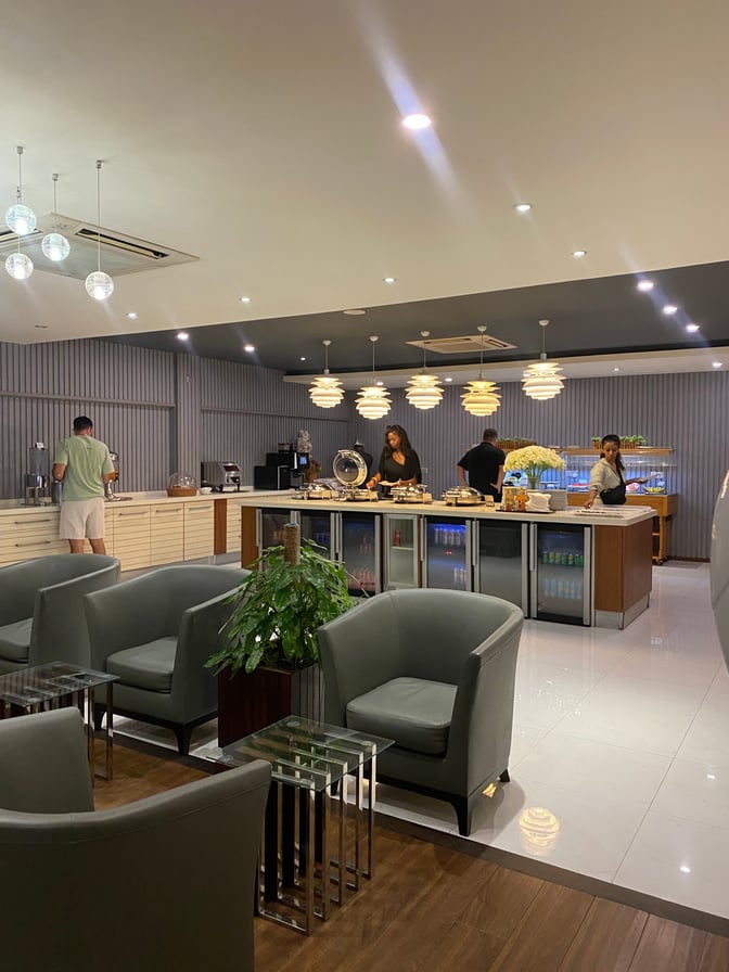 The Moonimaa Lounge at Velana International Airport features a self-serve food area with seating and beverage refrigerators.