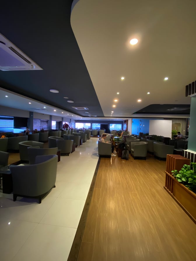 The Moonimaa Lounge at Velana International Airport features a seating area with armchairs and tables, offering a comfortable waiting space.