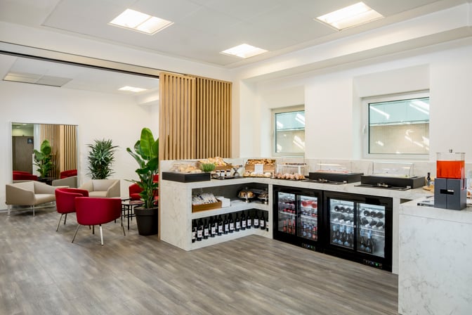Self-serve food and beverage area in the Aspire Executive Lounge at Venice Marco Polo Airport offers snacks, drinks, and seating.
