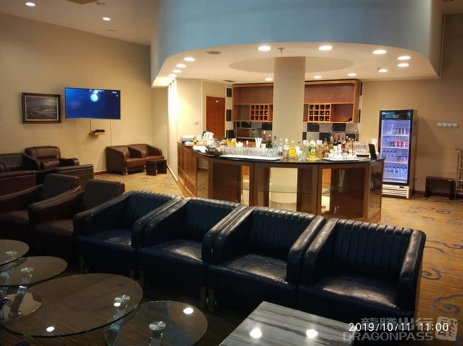 The Khami Lounge at Victoria Falls Airport features a central bar with a selection of beverages and surrounding seating areas.