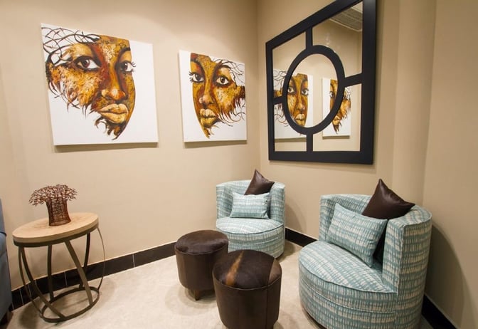 The seating area in Makuwa Lounge at Victoria Falls Airport features round chairs, small tables, and decorative wall art.