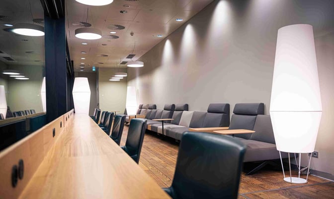 The Austrian Business Lounge at Vienna International Airport features a seating area with cushioned chairs and individual tables for travelers.