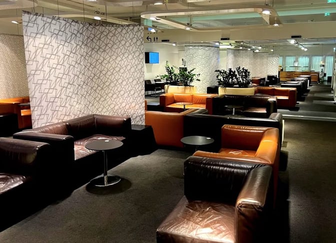 The Sky Lounge at Vienna International Airport features spacious seating areas with armchairs and small tables, providing a comfortable waiting environment.