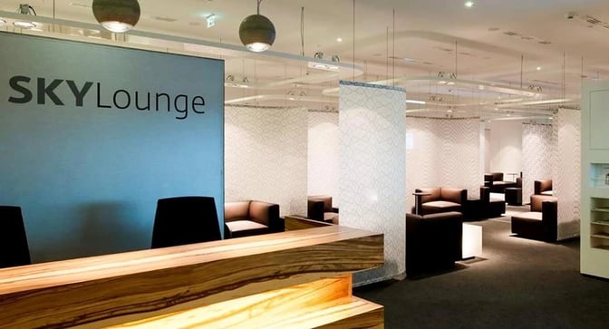 The Sky Lounge at Vienna International Airport features a reception desk and a seating area with partitioned sections for privacy.