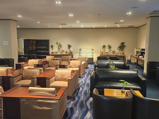 The Vientiane Airport VIP Lounge features comfortable seating with tables and a self-serve area offering snacks and beverages.