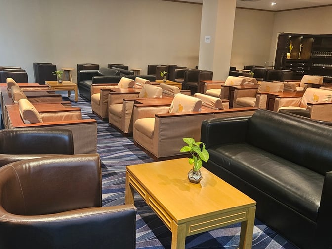 The Vientiane Airport VIP Lounge features a seating area with armchairs and small tables, providing a comfortable space for travelers.