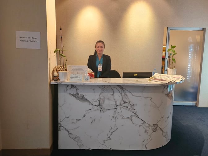 The reception desk at Vientiane Airport VIP Lounge features a staff member ready to assist guests with lounge access and information.