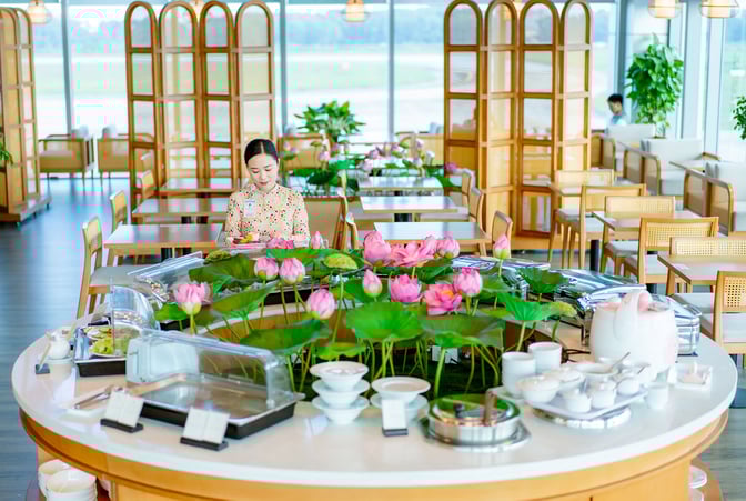 The SH Premium Lounge at Vinh Airport features a self-serve food station surrounded by seating, offering a variety of dining options.