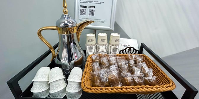 The refreshment station at Hayyak Lounge, Wadi al-Dawasir Airport, offers coffee with cups and a basket of packaged snacks.