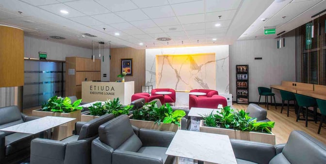 The Etiuda Executive Lounge at Warsaw Chopin Airport features comfortable seating with tables, a reception desk, and a magazine rack.