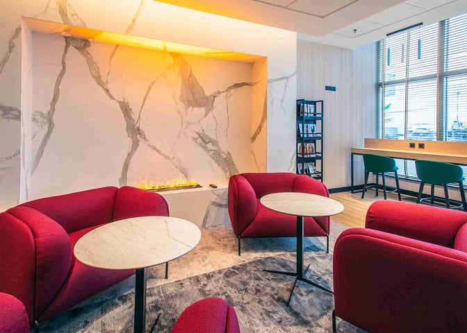 The Etiuda Executive Lounge at Warsaw Chopin Airport features comfortable seating with small tables, a decorative wall, and a reading area.