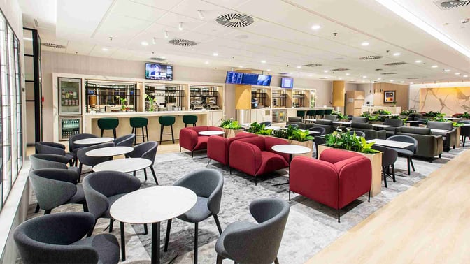 The Etiuda Executive Lounge at Warsaw Chopin Airport features a seating area with tables and chairs, and a bar offering refreshments.