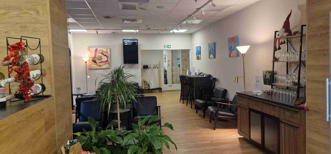 The Mazovia Premium Lounge at Warsaw-Modlin Airport features seating areas, a display of wine bottles, and a counter with glasses.