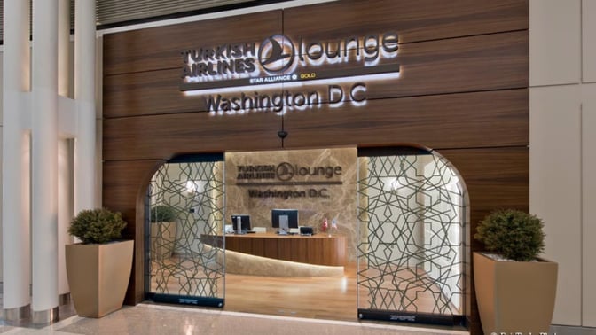 The entrance to the Turkish Airlines Lounge at Washington Dulles features a reception desk and decorative glass panels.