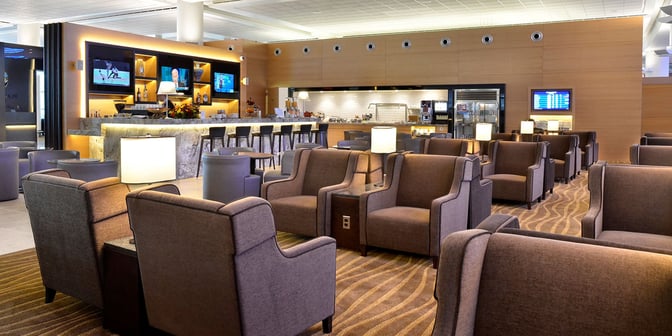 The Plaza Premium Lounge at Winnipeg Airport features a seating area with armchairs and a bar offering beverages and snacks.