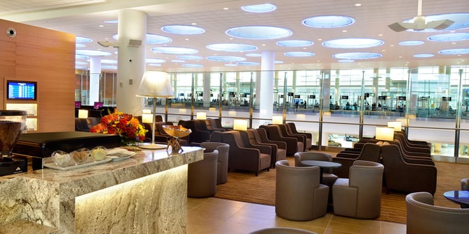 The Plaza Premium Lounge at Winnipeg Airport features comfortable seating with a view of the terminal and a refreshment counter.