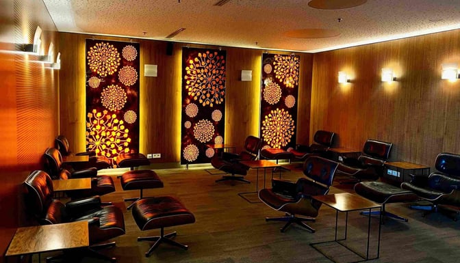 The Executive Lounge at Wroclaw–Nicolaus Copernicus Airport features comfortable seating with individual tables and decorative wall panels.
