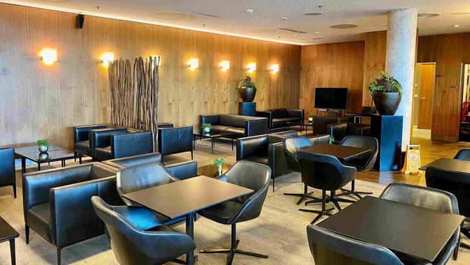 The Executive Lounge at Wroclaw–Nicolaus Copernicus Airport features comfortable seating with tables and a television for passenger relaxation.