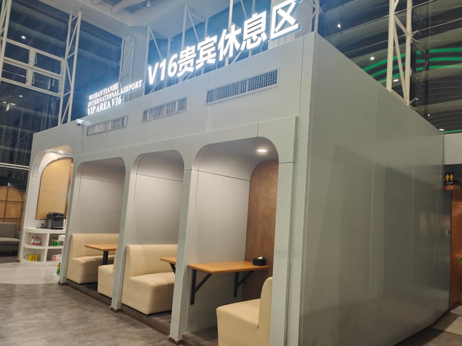 Booth seating in the V16 VIP Lounge at Wuhan Tianhe International Airport offers semi-private spaces with tables for travelers.