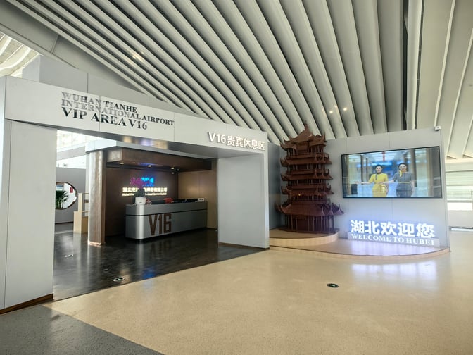 The entrance to the V16 VIP Lounge at Wuhan Tianhe International Airport features a reception desk and welcoming signage.