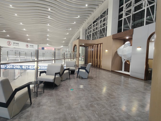The seating area in the V16 VIP Lounge at Wuhan Tianhe International Airport offers armchairs with views of the terminal gates.