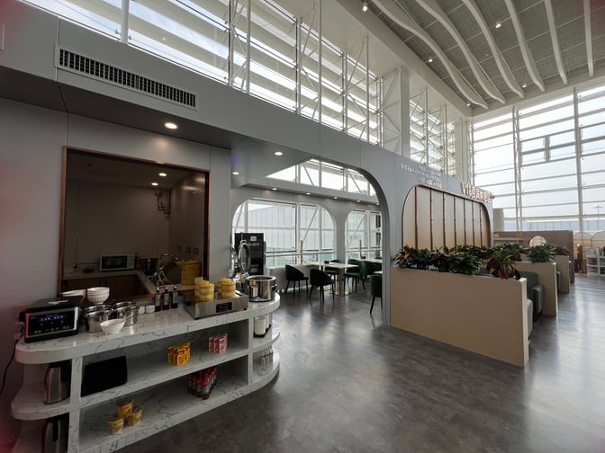 The V18 VIP Lounge at Wuhan Tianhe International Airport features a self-serve food station and seating area with tables and chairs.