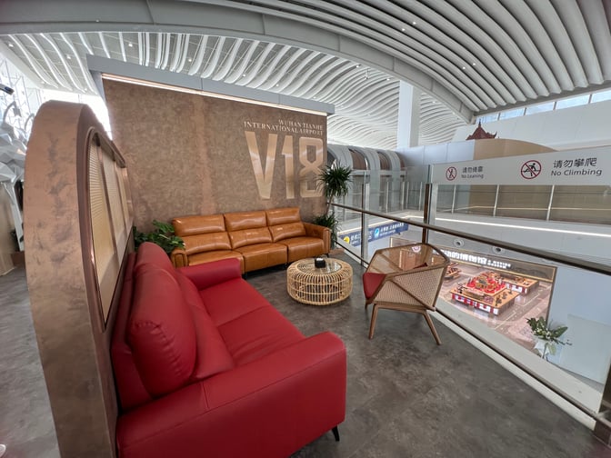 The V18 VIP Lounge at Wuhan Tianhe International Airport features a seating area with sofas and a view of the terminal below.