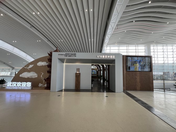 The entrance to the V18 VIP Lounge at Wuhan Tianhe International Airport features a welcoming sign and a digital display.