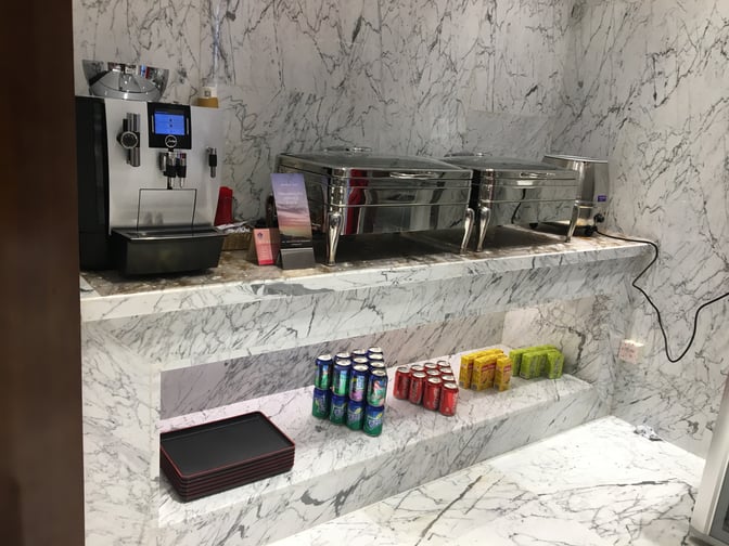 The First Class Lounge No.3 at Wuhan Tianhe International Airport features a self-serve beverage station with a coffee machine and assorted drinks.