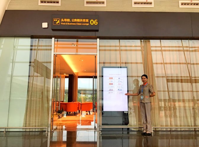 The entrance to the No. 6 Domestic First/Business Class Lounge at Wuhan Tianhe International Airport features a welcoming staff member and visible seating area.