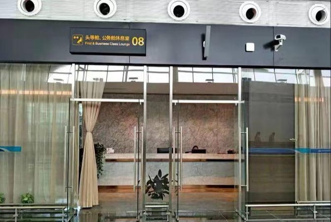 The entrance to First Class Lounge No.8 at Wuhan Tianhe International Airport features glass doors and a reception desk inside.