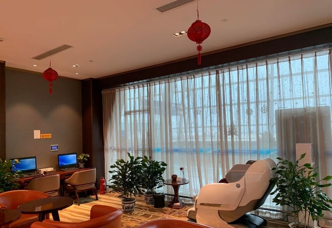 The First Class Lounge No.8 at Wuhan Tianhe International Airport features computer workstations and a massage chair for passenger comfort.