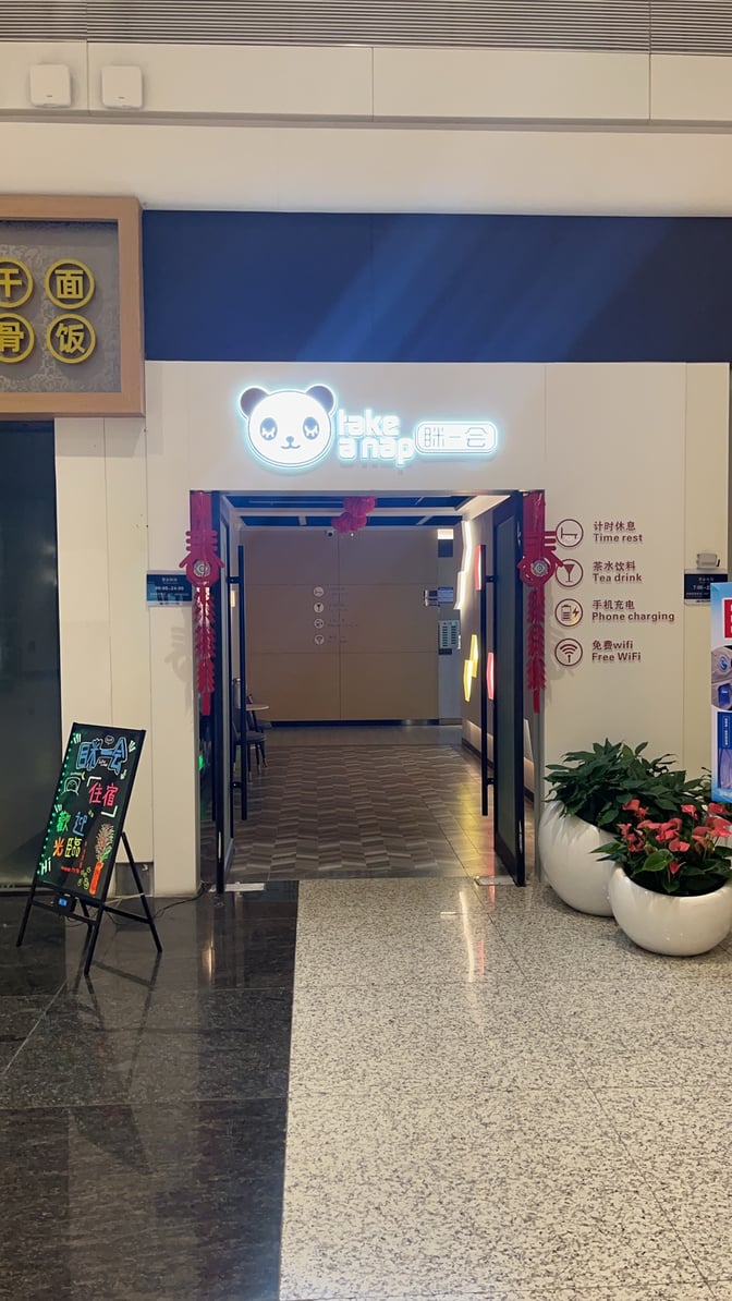 The entrance to the "Take a Nap" sleep pods at Wuhan Tianhe International Airport features signage for time rest, tea drinks, phone charging, and free WiFi.