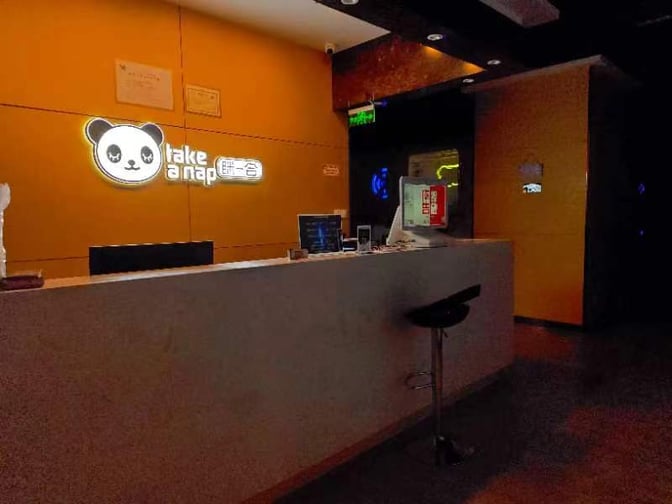 The reception area at Wuhan Tianhe International Airport's Take a Nap Sleep Pods features a counter with seating and check-in facilities.