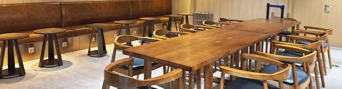The seating area in the V4 China Eastern Lounge at Wuhan Tianhe International Airport features a long communal table with chairs and side tables.