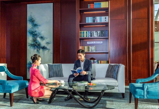 The seating area in Xiamen Gaoqi International Airport's First Class Lounge features a sofa, armchairs, and a bookshelf for relaxation.