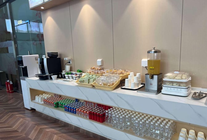 Self-serve snack station at China Southern Pearl Lounge, Xi'an Airport, offers pastries, sandwiches, beverages, and a coffee machine.