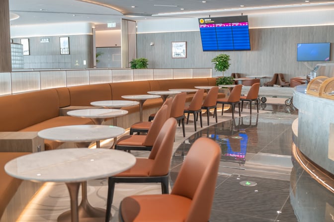 Seating area in China Eastern Lounge at Xi'an Xianyang Airport features round tables and chairs with a view of the flight information screen.