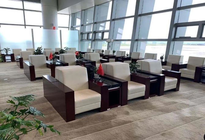 The seating area in First Class Lounge 02 at Xingyi Wanfenglin Airport features armchairs and tables with runway views.