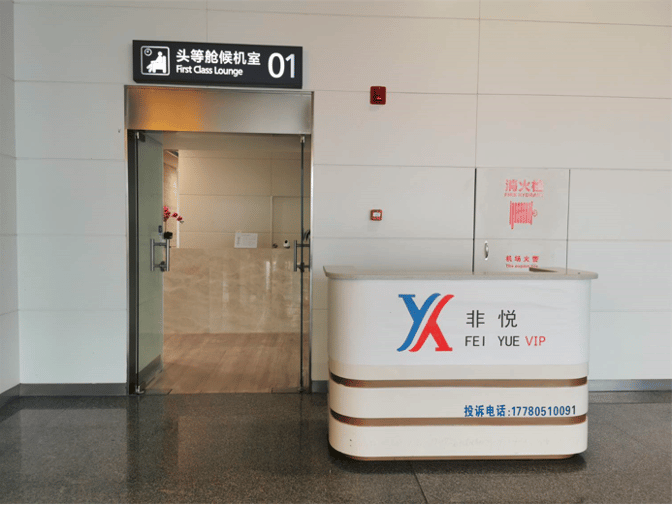 The entrance to First Class Lounge 01 at Xingyi Wanfenglin Airport features a reception desk and glass doors.