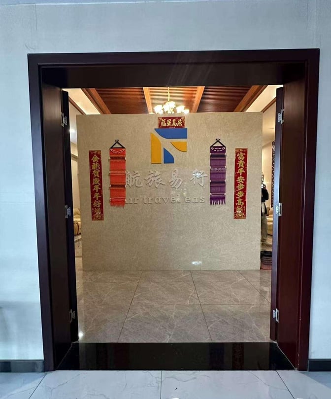 The entrance to the Best Business Lounge at Xishuangbanna Gasa Airport features a sign with decorative wall hangings.
