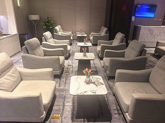 The seating area in First Class Lounge 2 at Yan'an Ershilipu Airport features comfortable armchairs and small tables with floral arrangements.