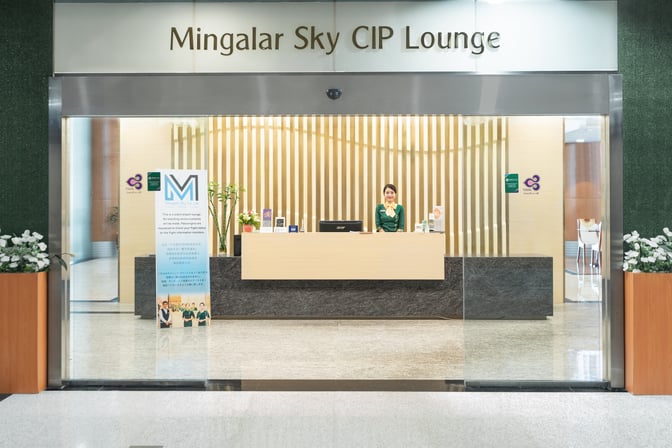 The entrance to Mingalar Sky CIP Lounge at Yangon International Airport features a reception desk with a staff member ready to assist.