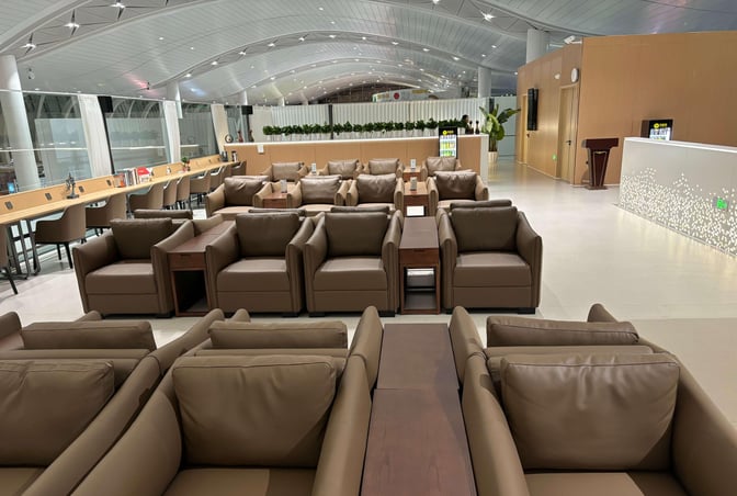 The First Class Lounge at Yinchuan Hedong International Airport features spacious seating with armchairs and a work area with desk seating.