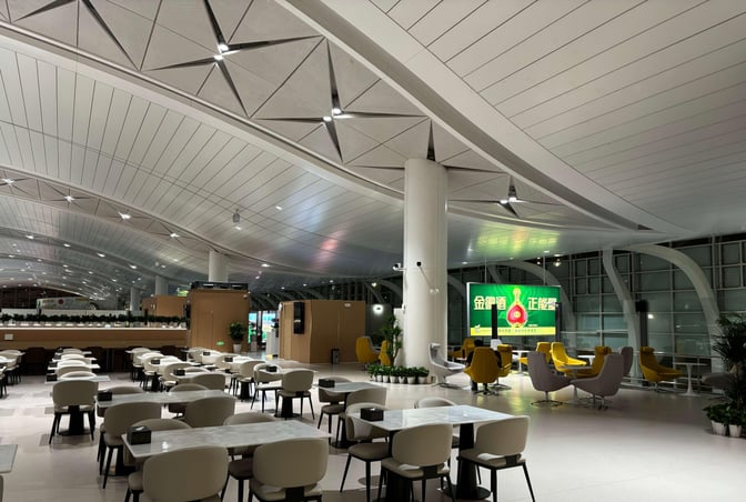 The First Class Lounge at Yinchuan Hedong International Airport features spacious seating areas with tables and chairs for dining and relaxation.