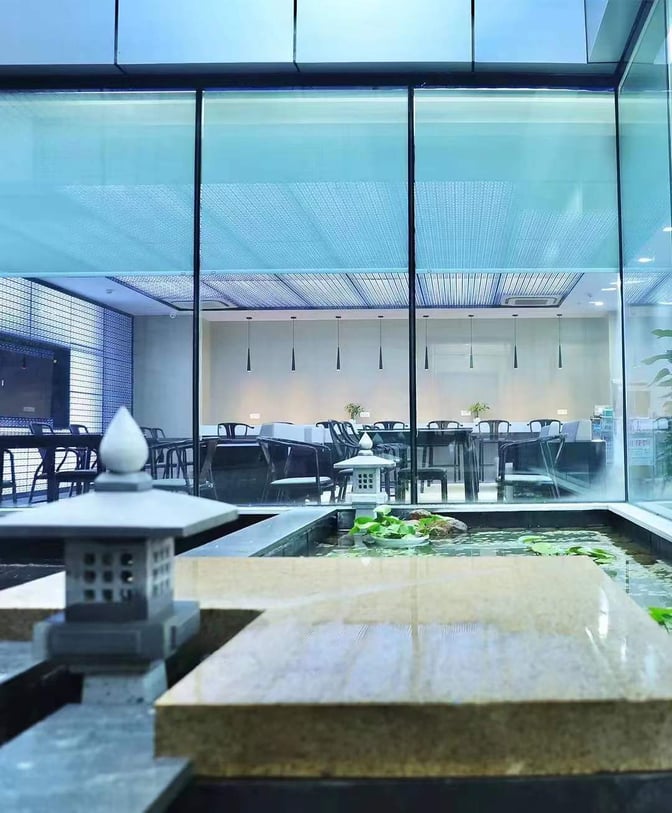 The First Class Lounge at Yiwu Airport features a seating area visible through glass, adjacent to a decorative water feature.