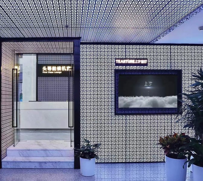 The entrance to the First Class Lounge at Yiwu Airport features a patterned wall and glass doors, with signage above.