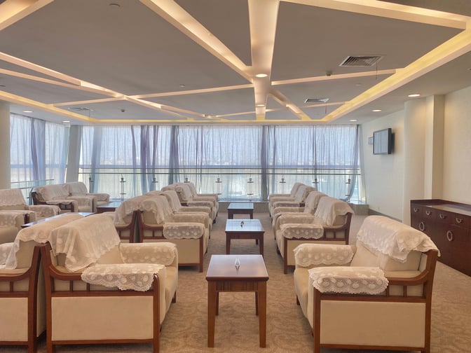 The seating area in Yiwu Airport's First Class Lounge features armchairs with lace covers and tables, offering a comfortable waiting space.