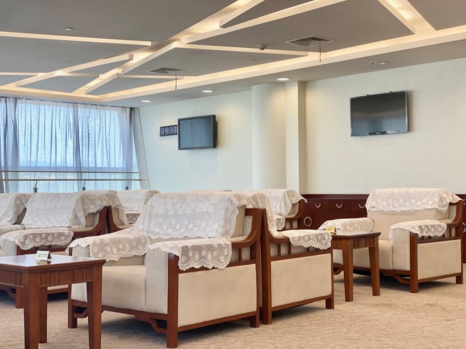 The seating area in Yiwu Airport's First Class Lounge features armchairs with lace covers and small tables, offering a comfortable waiting space.